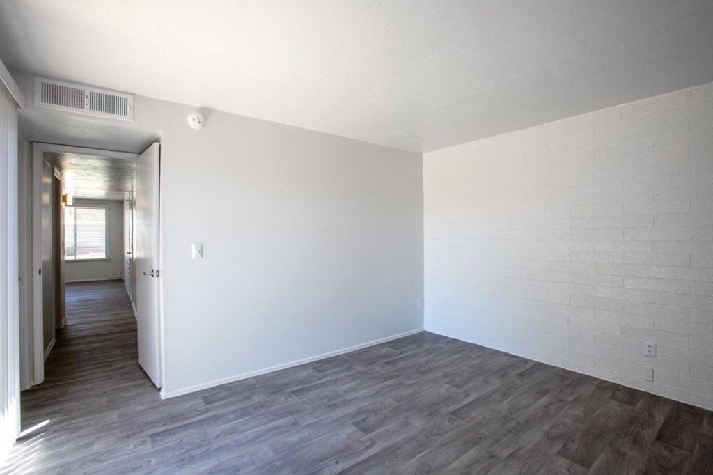 A room with a white wall and wooden floor.