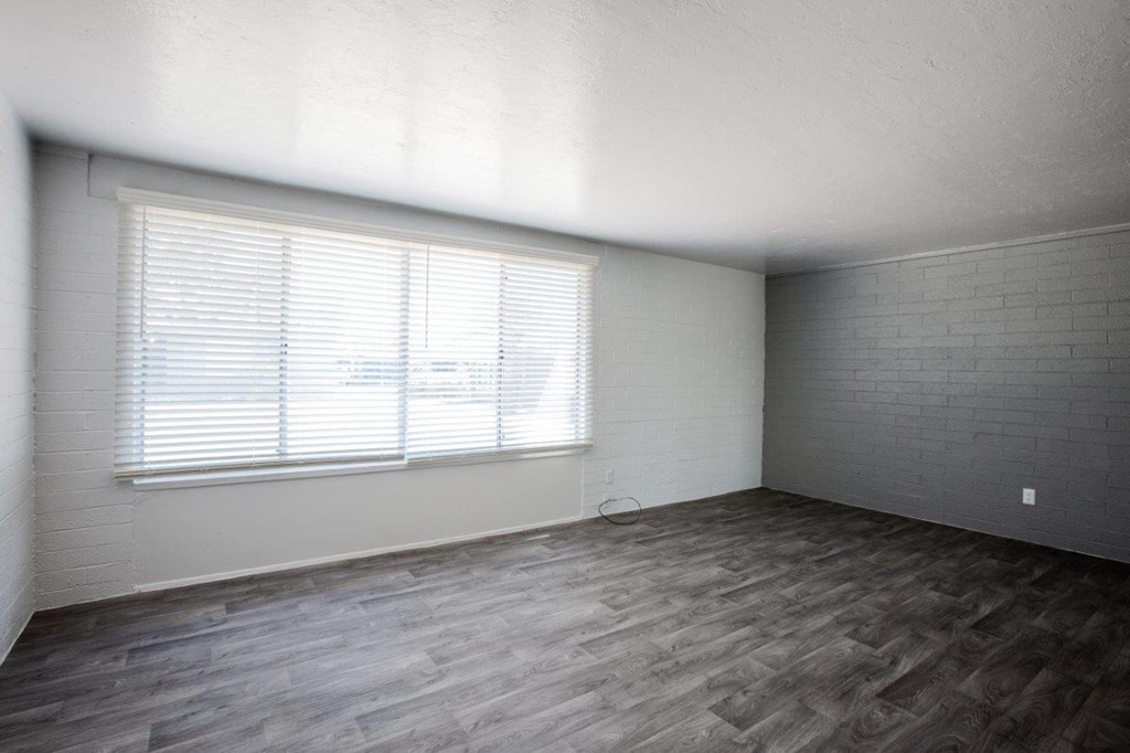 A room with a window and wooden flooring.