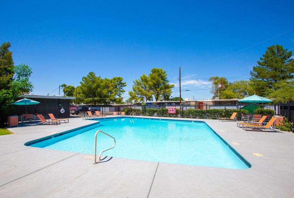 A large swimming pool with a diving board and lounge chairs.