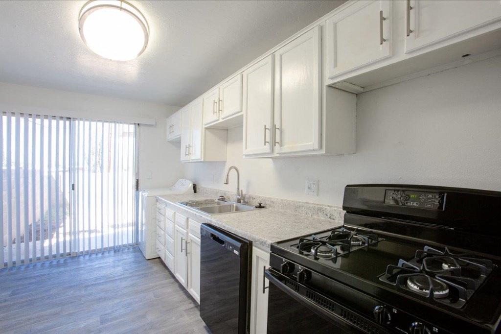 A kitchen with black stove and white cabinets.