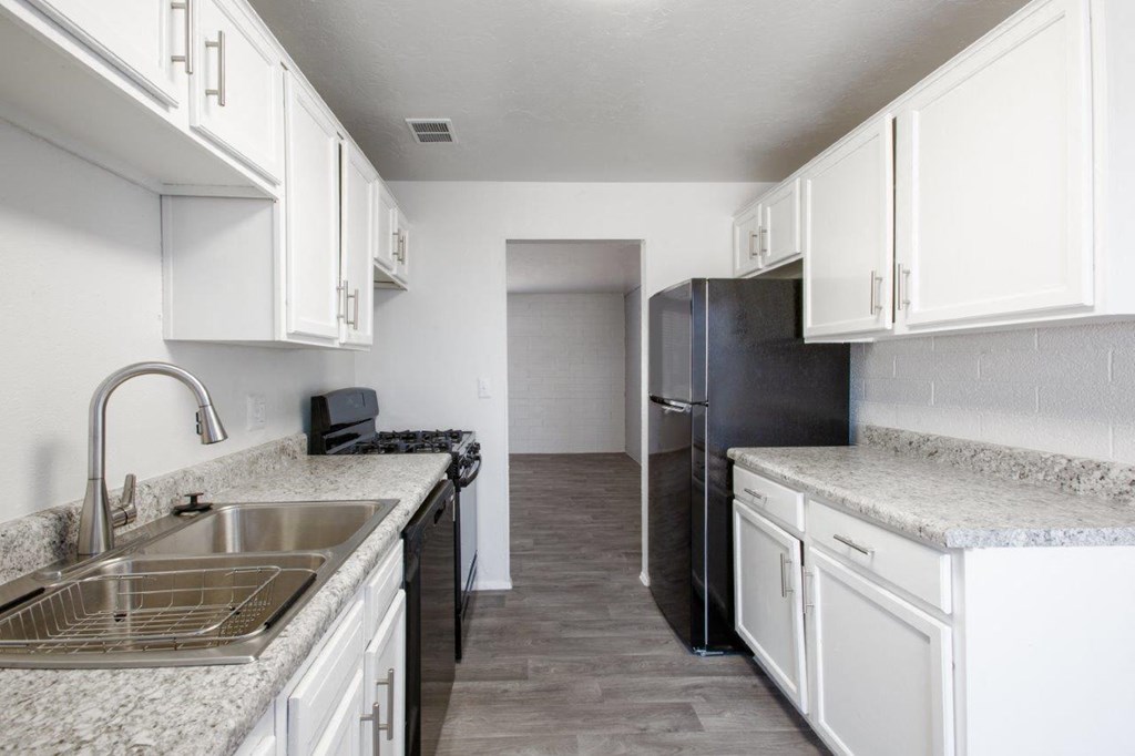 A kitchen with white cabinets and a granite countertop.