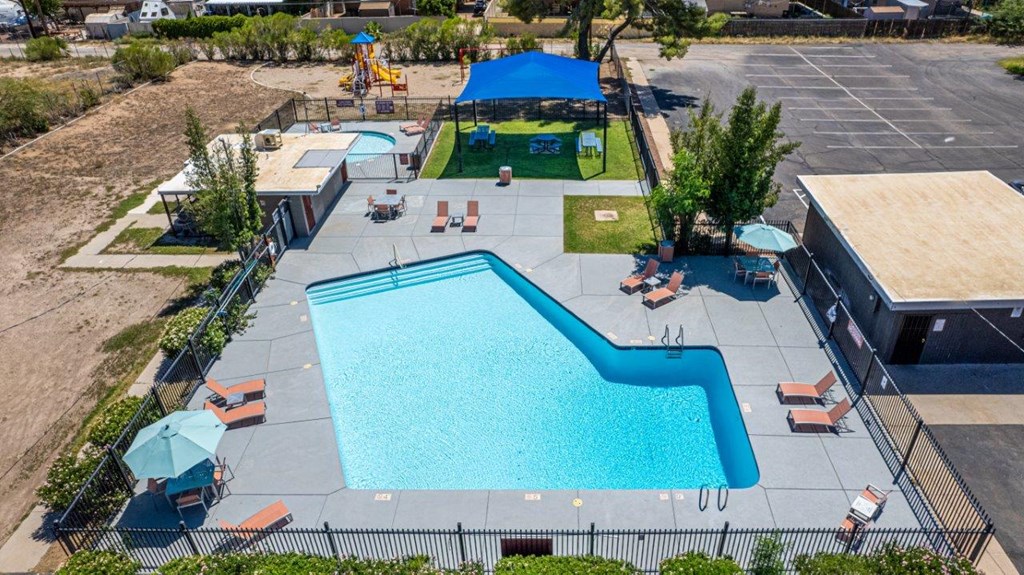 A large outdoor swimming pool surrounded by a fence and lounge chairs.