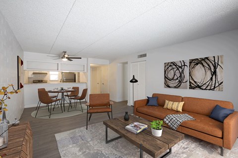 A living room with a brown couch, a coffee table, and a dining table with chairs.