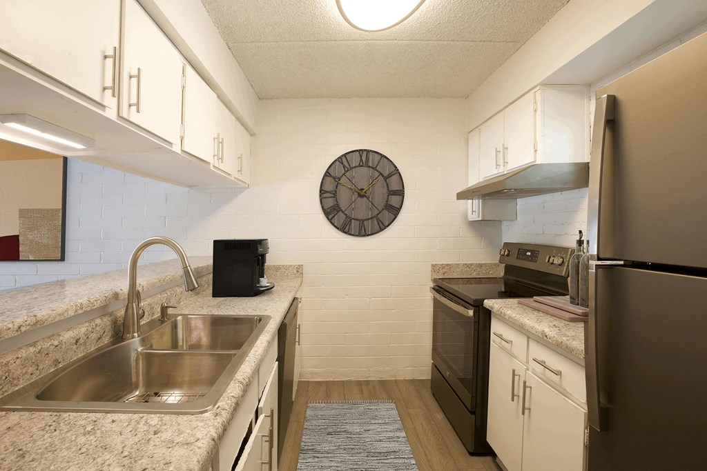 A kitchen with a clock on the wall and a refrigerator on the right.