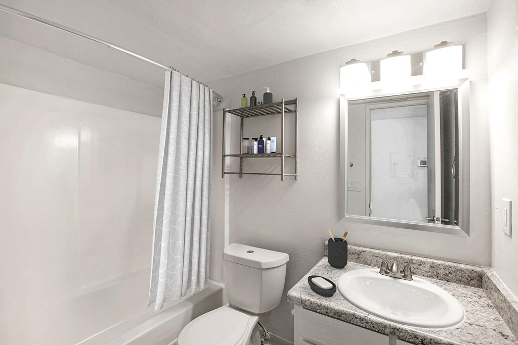A bathroom with a white sink, toilet, and a white bathtub with a white shower curtain.