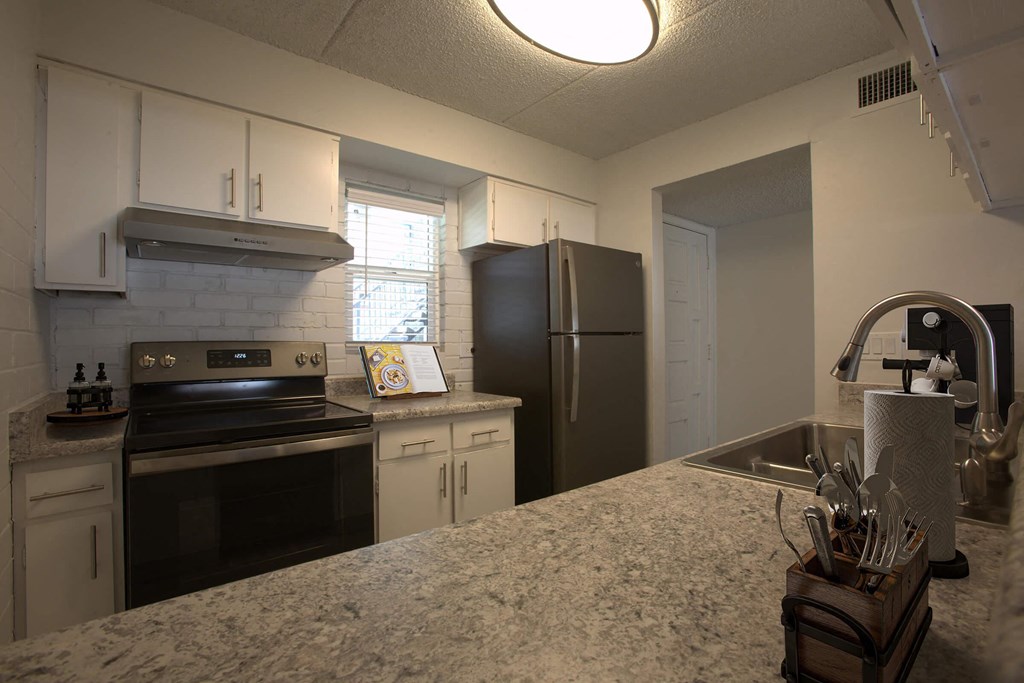 A kitchen with a stove, refrigerator, and sink.