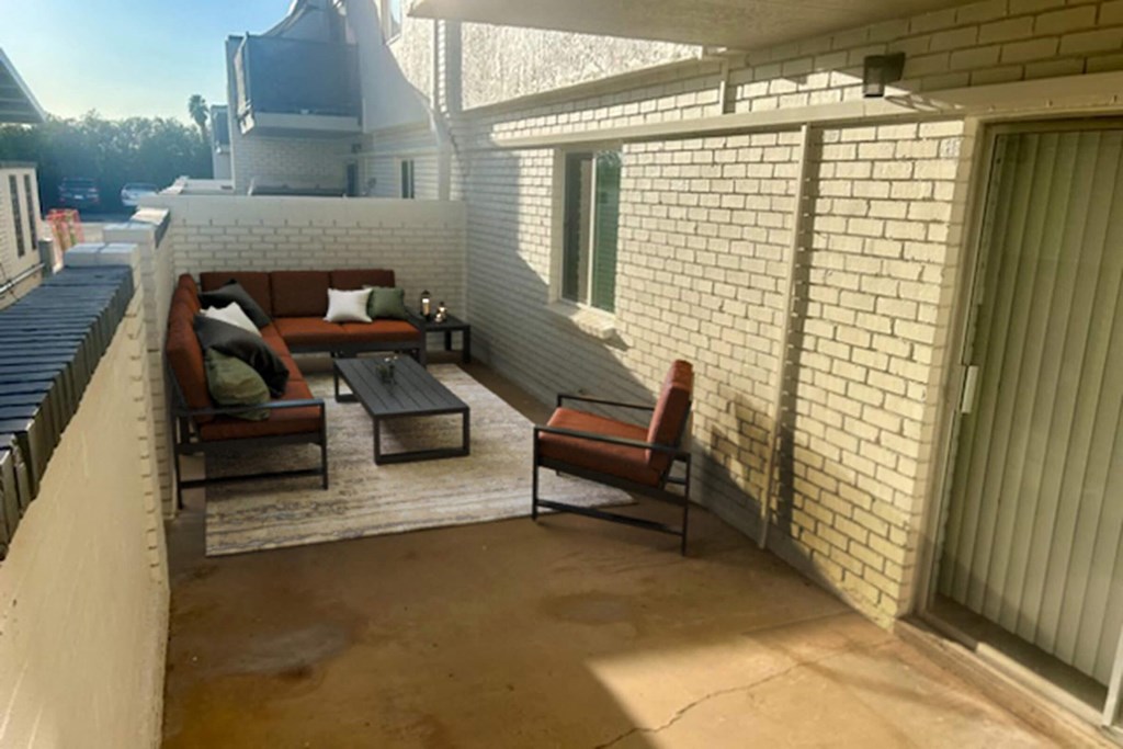 A patio with a couch, table, and chairs.