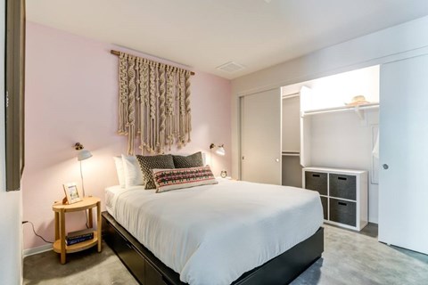 A bedroom with a bed, nightstand, and a window with curtains.