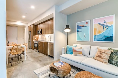 A living room with a white couch and a painting of a man on a surfboard.