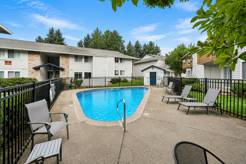 A pool surrounded by chairs and a fence.