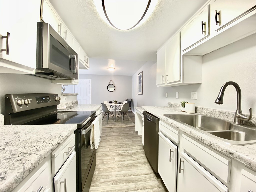A kitchen with black appliances and white cabinets.