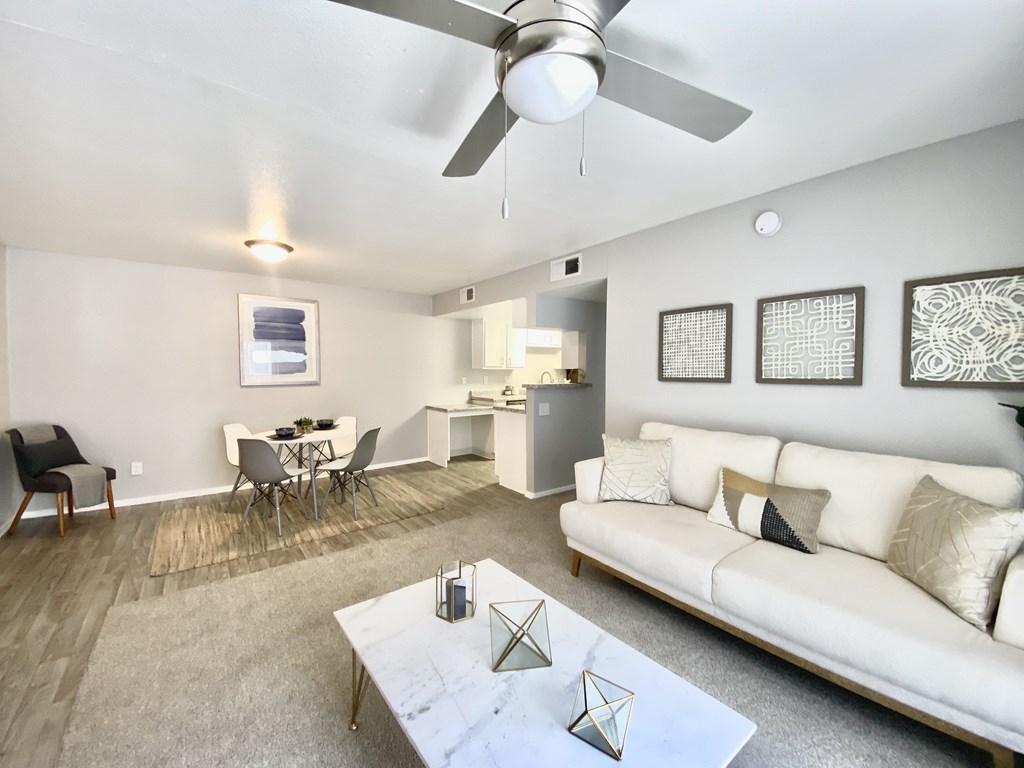 A living room with a white couch, a dining table, and a ceiling fan.