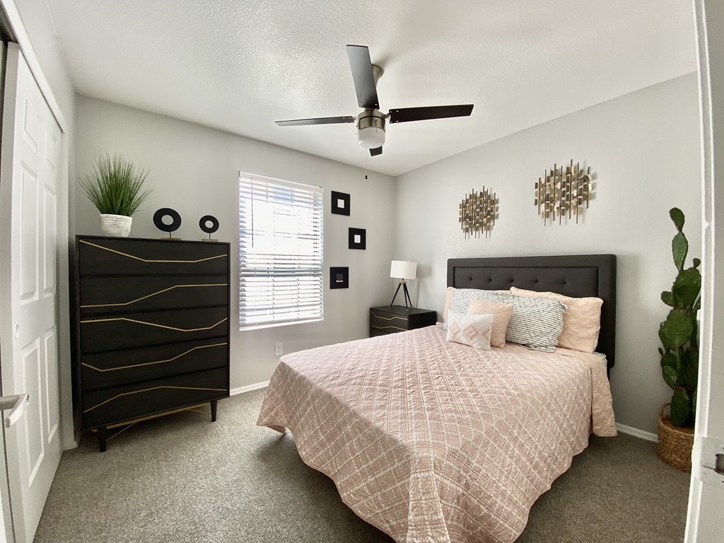 A bedroom with a bed, dresser, and ceiling fan.