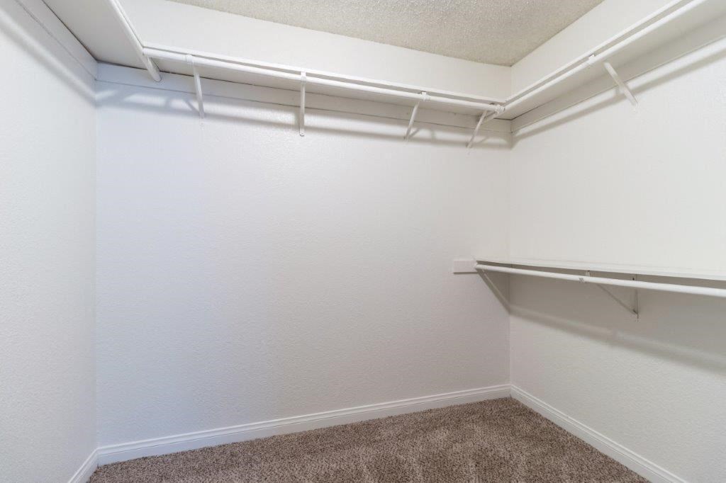 a walk in closet with a hanging rack on the wall