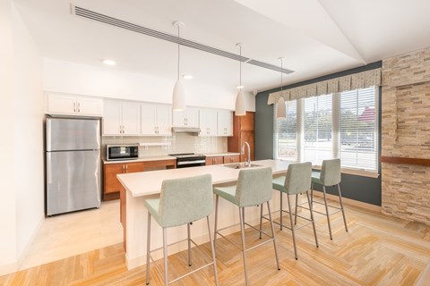 A kitchen with a refrigerator, sink, and bar stools.