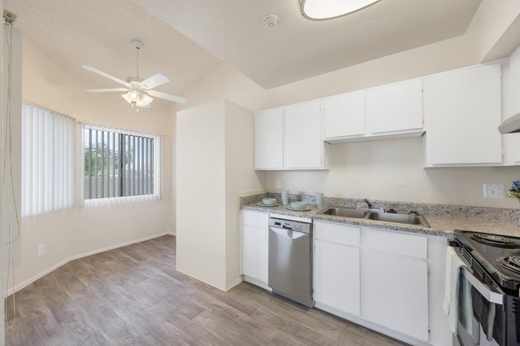 A kitchen with white cabinets and a fan.
