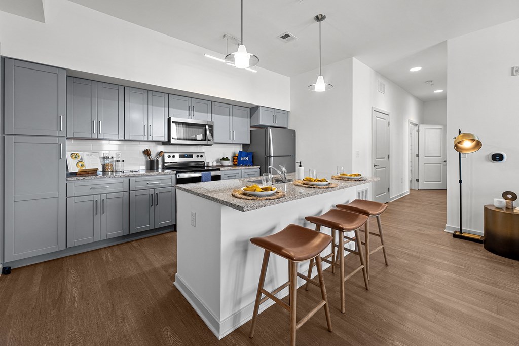 a kitchen with gray cabinets and a white island with three stools