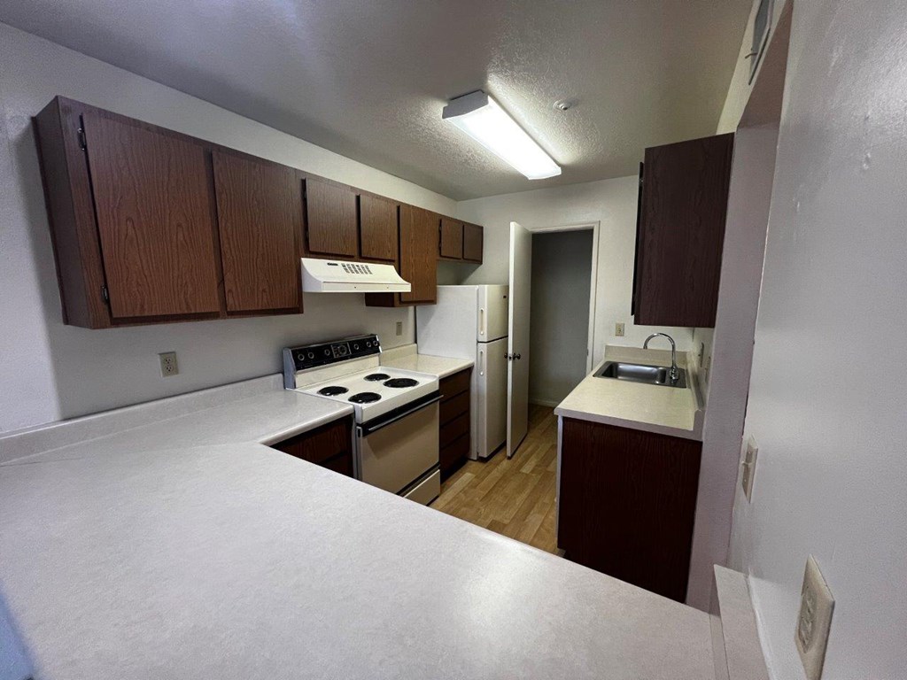 A kitchen with white countertops and brown cabinets.
