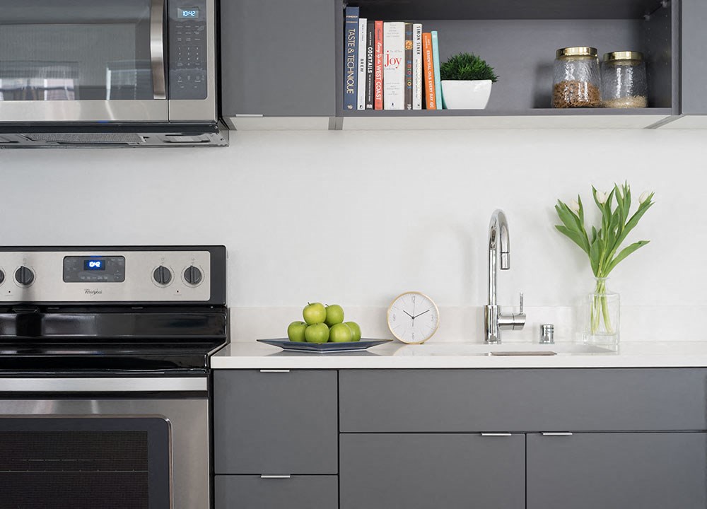 a kitchen with gray cabinets and a clock and a sink