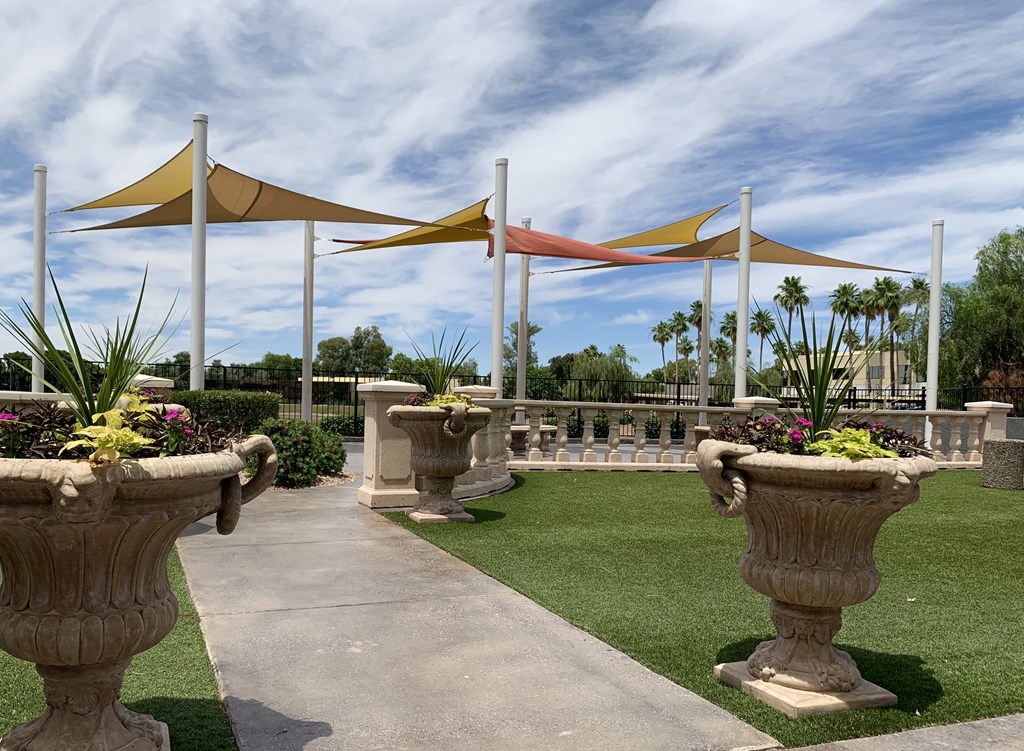 a garden area with stone vases with flowers and flags