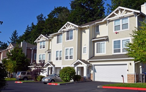 A row of townhouses with a car parked in front of the first one.