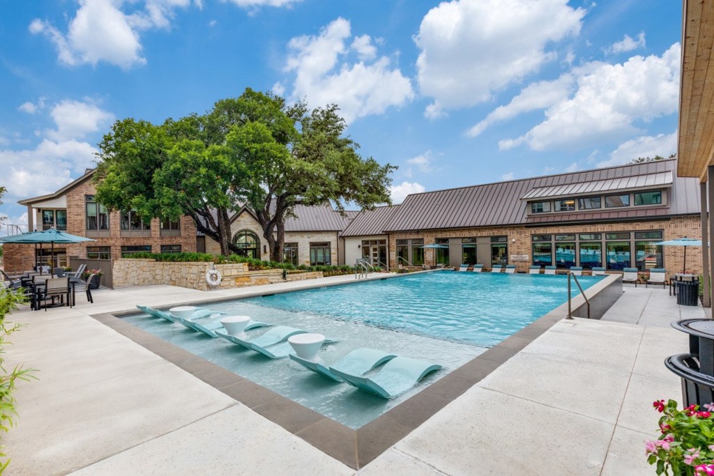 A large outdoor swimming pool with a slide and a building in the background.