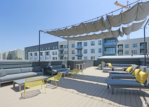 a roof deck with couches and chairs in front of a building with a crane in the
