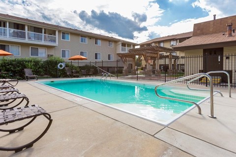 A swimming pool surrounded by a metal fence and chairs.