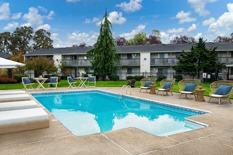 A swimming pool surrounded by lounge chairs and trees.