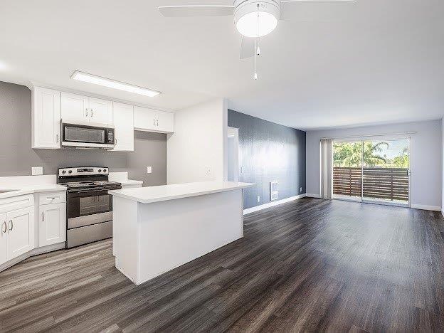 A kitchen with white cabinets and a wooden floor.
