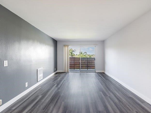 A room with grey walls and wooden flooring with a window and a door.