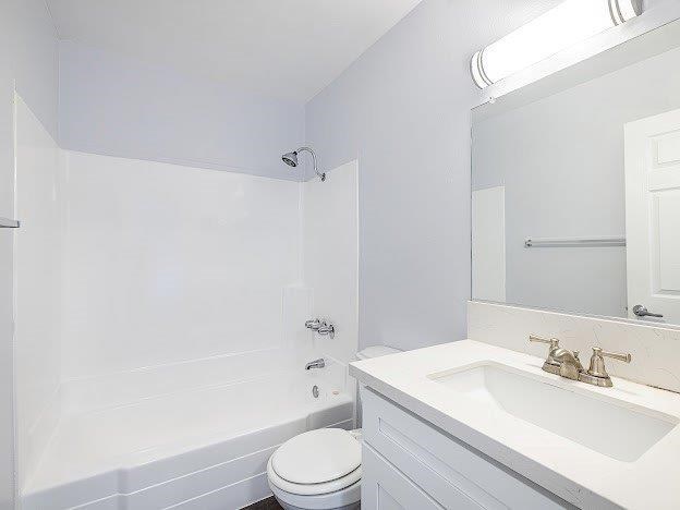 A white bathroom with a toilet, sink, and shower.