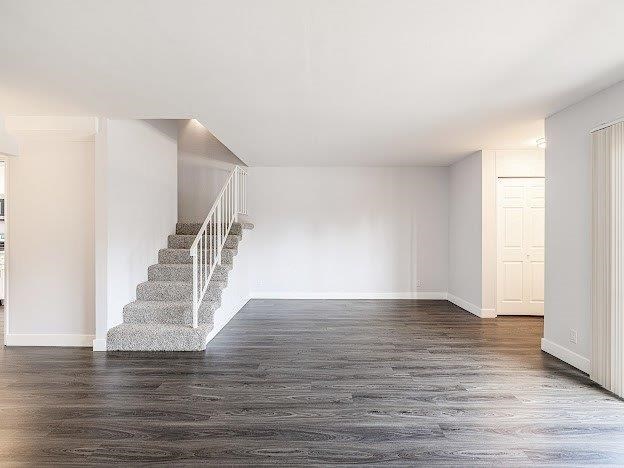 A spacious room with a staircase and wooden flooring.