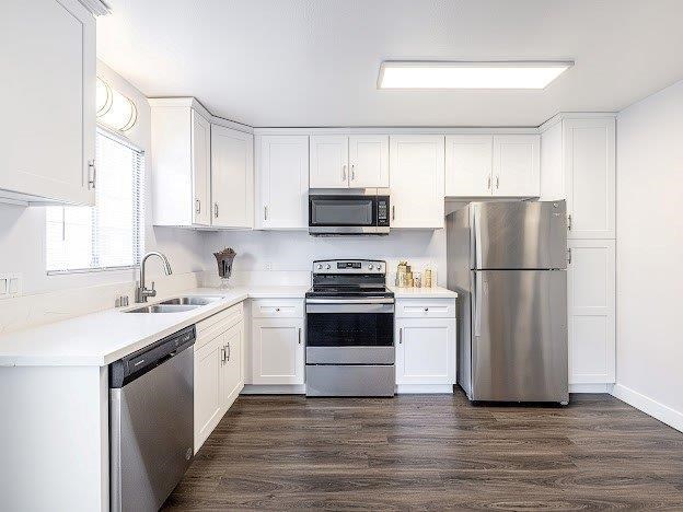 A kitchen with white cabinets and a stainless steel refrigerator.