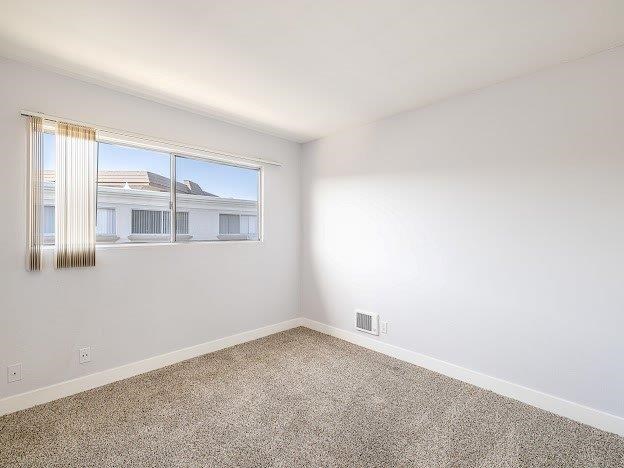 A room with a window and a carpeted floor.