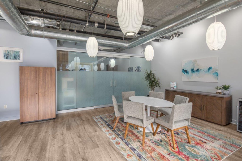 A room with a glass wall, wooden floors, and a white table with chairs.