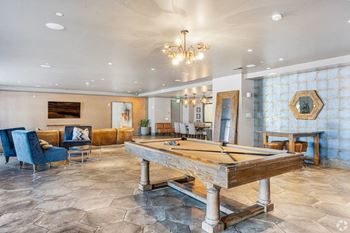 A pool table is in the middle of a room with a blue chair and a mirror.