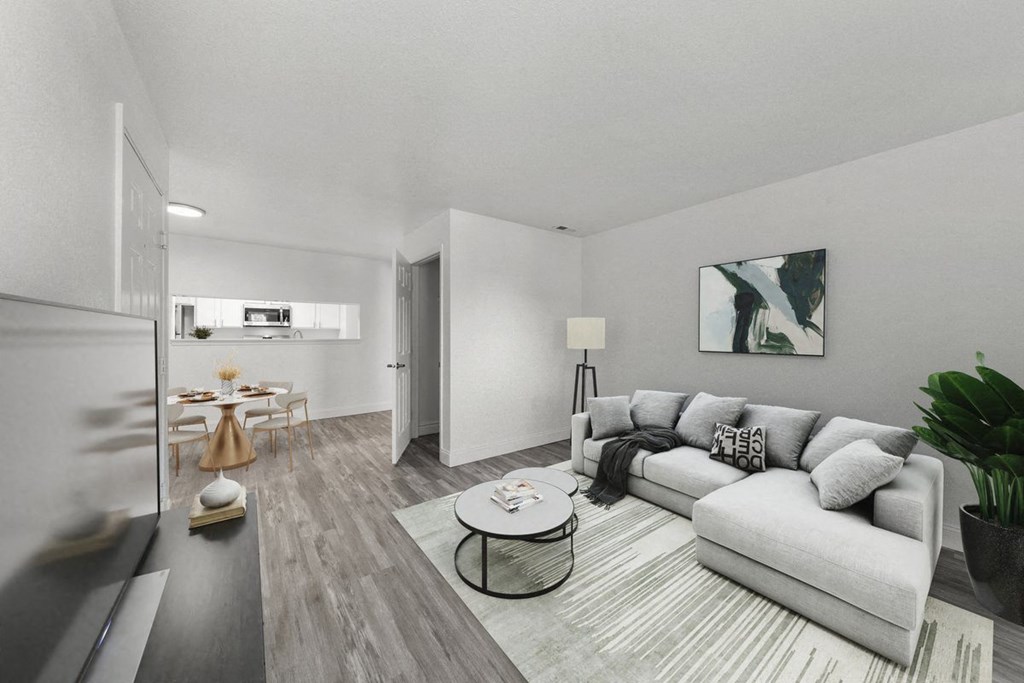 a living room with a couch coffee table and a dining room table in the background