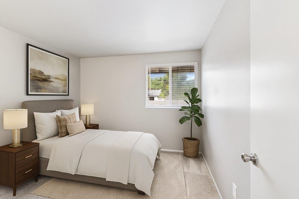 A bedroom with a bed, nightstands, and a plant.