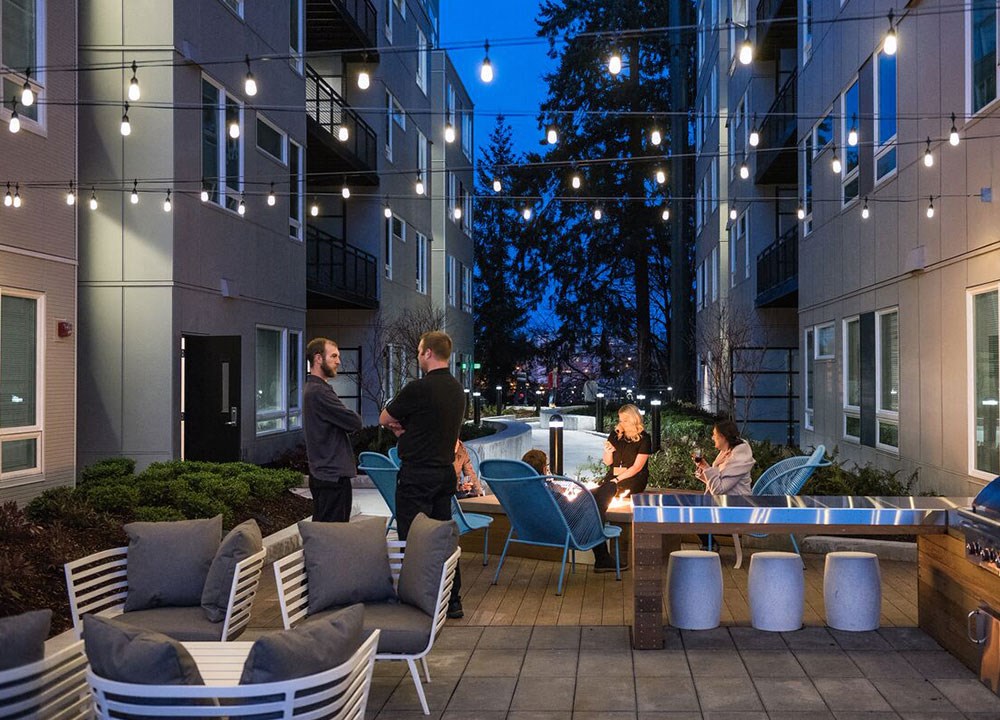 two men shaking hands at an outdoor patio with tables and chairs