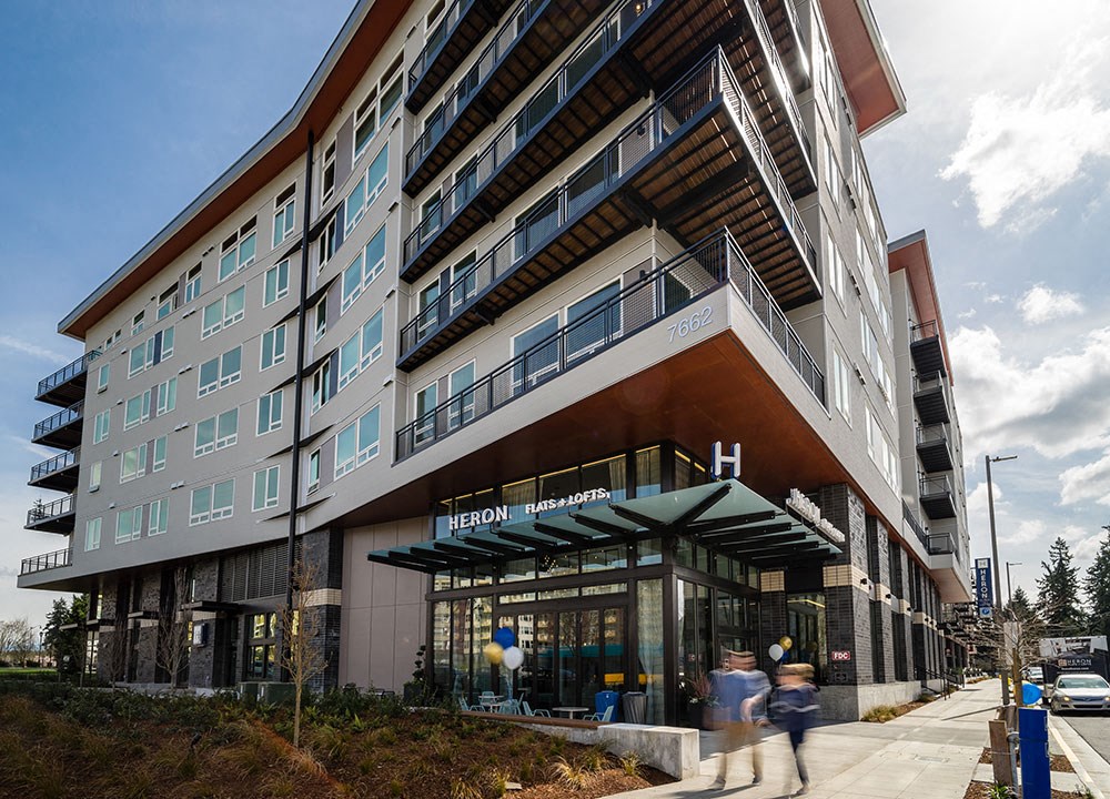 people walking in front of a building on a sidewalk