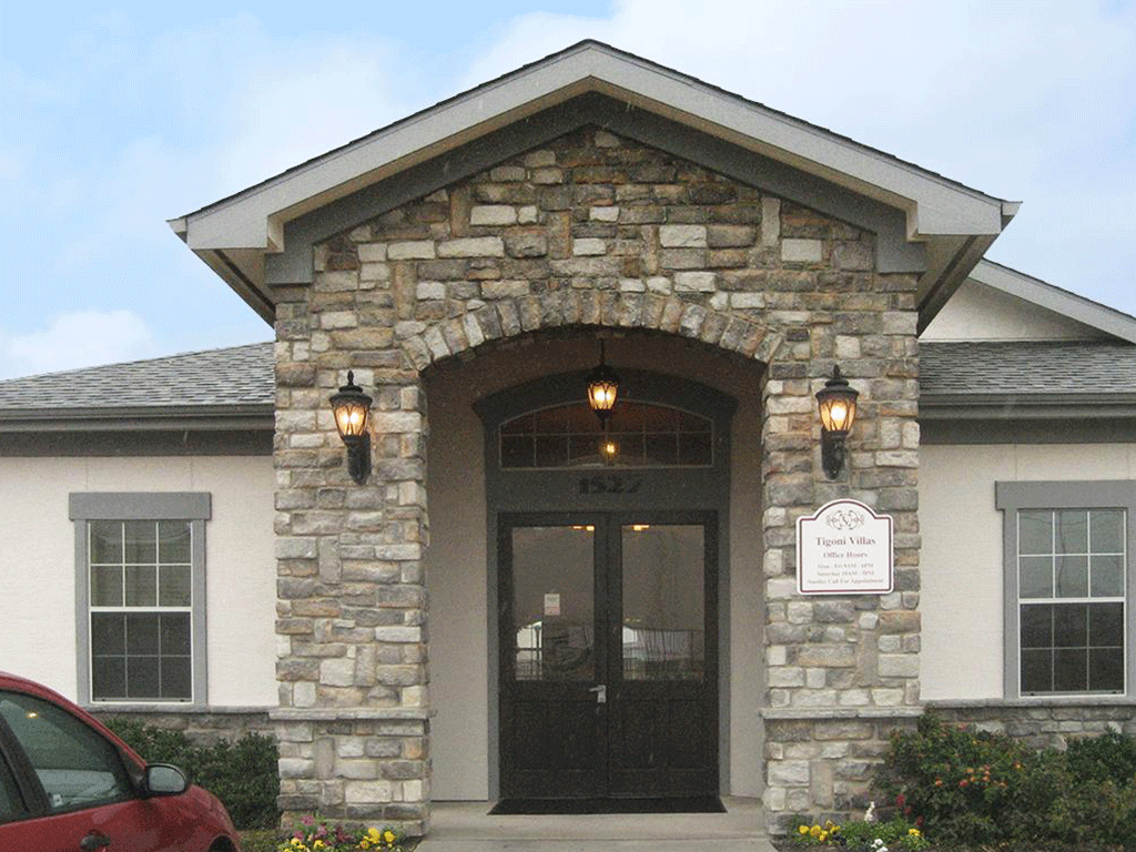 the front entrance of a stone building with a black door