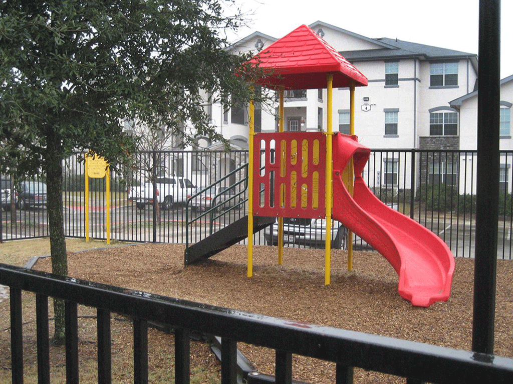 a playground with a red slide in a park