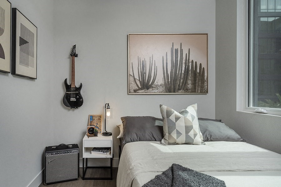 a small bedroom with a bed and a guitar on the wall