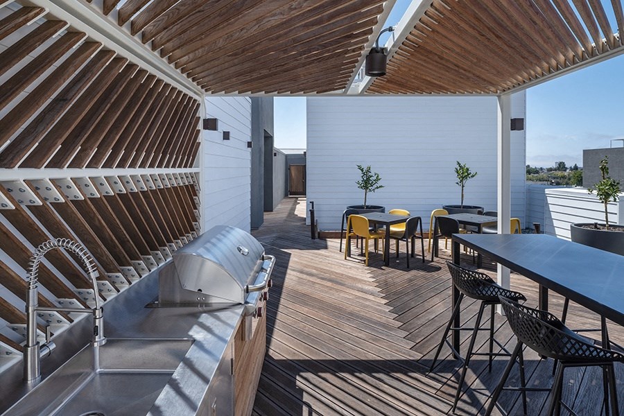 a rooftop deck with a grill and table and chairs