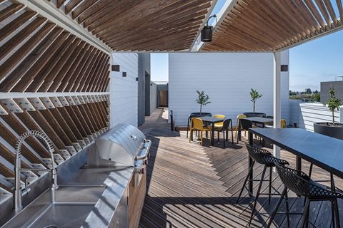 a rooftop deck with a grill and table and chairs