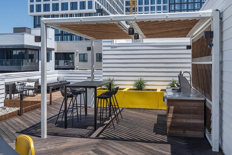 a pergola on a rooftop patio with a kitchen and dining area