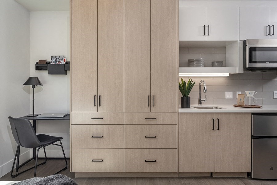 a kitchen with white cabinets and a white countertop with a sink and a microwave