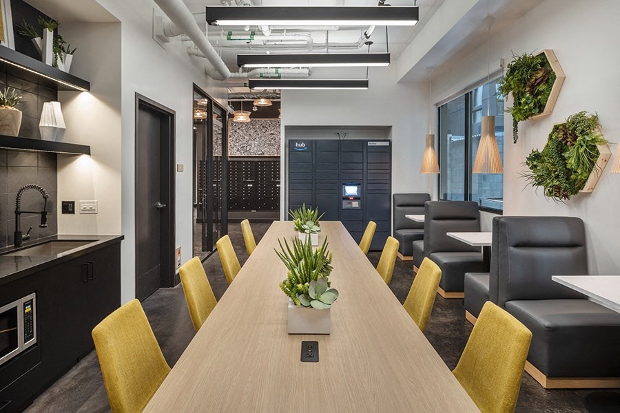 a large wooden table with yellow chairs and a kitchenette in the background