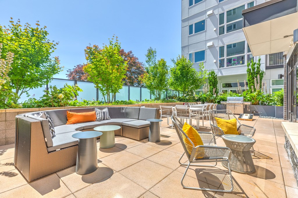 a patio with couches tables and chairs and a building in the background